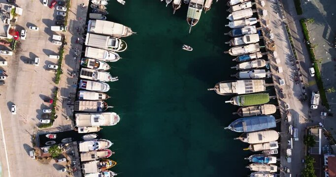 Aerial top down overview of Kas, Antalya, showing the coastal town with boats docked in the harbor, crammed together
