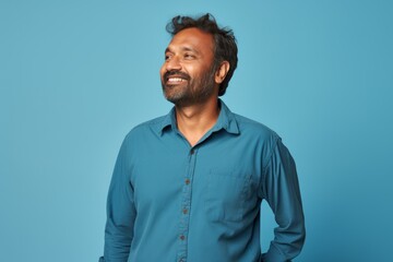 Obraz premium Portrait of a glad indian man in his 40s sporting a breathable hiking shirt while standing against soft blue background
