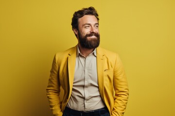 Obraz premium Portrait of a happy man in his 30s dressed in a stylish blazer on soft yellow background
