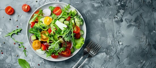 Fresh vegetable and cheese salad on a gray background with a fork and copy space image