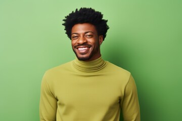 Fototapeta premium Portrait of a cheerful afro-american man in his 30s wearing a classic turtleneck sweater isolated on soft green background