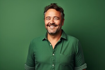 Fototapeta premium Portrait of a grinning man in his 40s wearing a comfy flannel shirt in soft green background