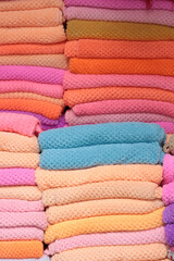 Stacks of bright purple and orange blankets or scarves.