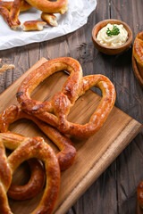 A fresh batch of golden-brown pretzels rests on a wooden cutting board, ready to be served. The warm, crispy texture and simple presentation create a perfect snack-time treat, perfect for sharing