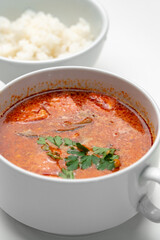 Bowl of curry with pieces of meat and a side of steamed rice arranged neatly for a meal