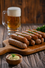 A delicious stack of grilled sausages served on a wooden board, garnished with parsley, and accompanied by a creamy dipping sauce. In the background, a frothy glass of beer