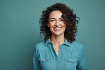Portrait of a smiling woman in her 40s sporting a versatile denim shirt isolated in soft teal background