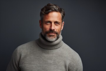 Obraz premium Portrait of a tender man in his 40s wearing a classic turtleneck sweater in front of soft gray background