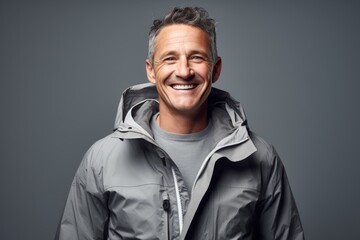 Fototapeta premium Portrait of a happy man in his 40s dressed in a water-resistant gilet over soft gray background