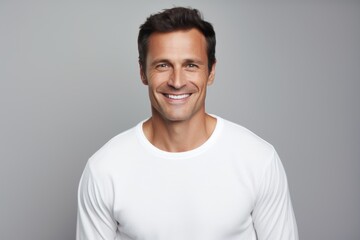 Fototapeta premium Portrait of a grinning man in his 40s sporting a long-sleeved thermal undershirt in front of soft gray background