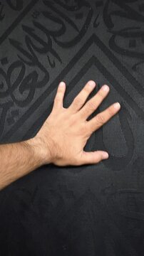 A man is touching the Holy Kaaba at Masjid al-Haram in Makkah, Saudi Arabia.