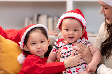 Parents and their two children are dressed in Christmas outfits to celebrate the Christmas holiday at home