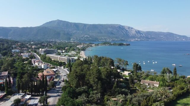 Ascending drone flight over Corfu Island reveals Dassia Bay and lush scenery in Greece