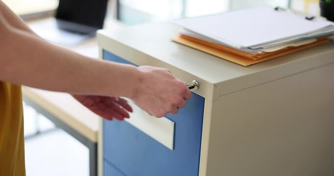 Woman hand opens metal box in office with key. Safety of business documents