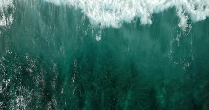 Aerial view of a wave crashing on winter beach covered in snow