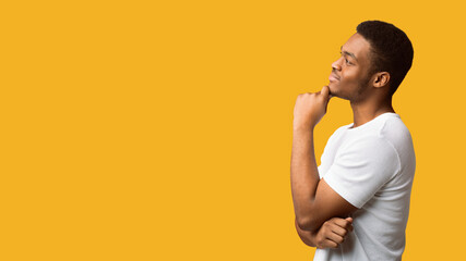 Making Decision. Side view of black guy looking at copy space, thinking about purchase, panorama,...