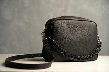 Stylish women's bag on gray background. Black leather handbag, close-up