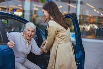 Senior Woman Receiving Help from Friend to Exit Car