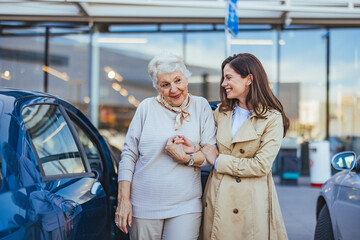 Young Woman Assisting Elderly Woman Near Car in Urban Setting