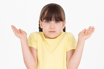 Teenager girl with yellow t-shirt having doubts while raising hands and shoulders on white background