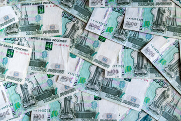 Russian money rubles with a face value of one thousand rubles lie on the entire background of the image, green and expensive