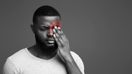 African guy rubs his eye, suffering from conjunctivitis, ocular diseases concept