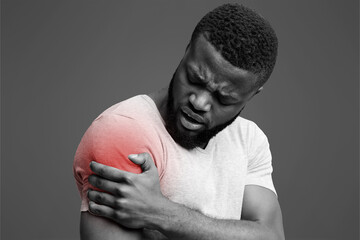 Young afro guy rubbing his itching forearm over white background, having rash