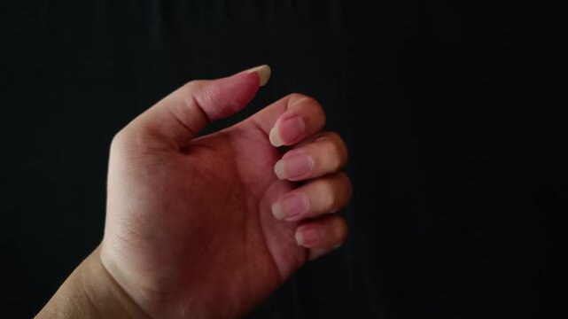 hand showing long clean nails, black background, copy space	