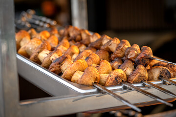 Mushrooms kebab (shish kebab) in close-up. Champignons fried on fire (barbecue) on skewers on the market counter. Delicious and mouth-watering vegan shashlik