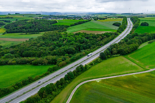 cargo truck and cars on the highway. asphalt road among green forest and beautiful rain clouds. cargo delivery and transportation concept
