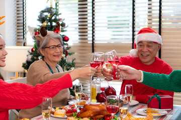 Family members are toasting with wine and drinks while sharing a meal together during the Christmas celebration at home