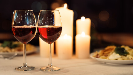 Romantic Date Dinner Background. Two Glasses Of Red Wine On Served Table With Food And Burning Candles In Restaurant. Panorama