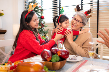 A little granddaughter lovingly hugs her grandmother, while they eating a meal together during the Christmas celebration at home