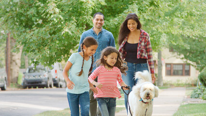 Smiling Family Outdoors Walking Dog Along Suburban Street