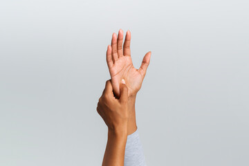African woman rubbing her painful palm, cropped, grey background