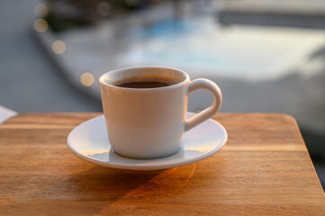 a cup of black Turkish coffee on the balcony with a swimming pool in the background