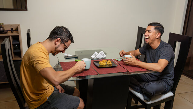 Joyful gay couple enjoying a meal together at home - Powered by Adobe