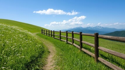 Fototapeta premium Path winding through rolling hills of wildflowers, with a wooden fence following the curves of the landscape and a distant mountain range
