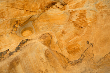 Natural texture background of sandstone rocks with lines, curves, prints in the As Amoeiras and Formosa beach cliffs in Santa Cruz, Portugal.