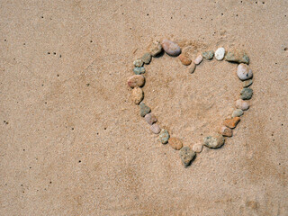 Set of colorful pebbles forming a shape on beach sand background © Roberto