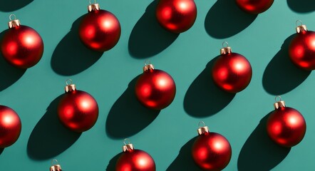 Red Christmas ornaments on a teal background with dramatic shadows for the holidays