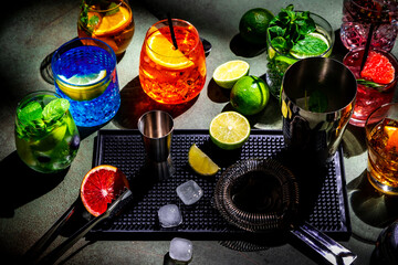 Alcoholic cocktails and bar tools on green background, top view