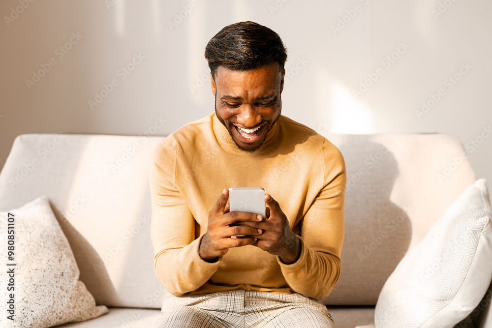 Aufkleber mobile gaming. excited afro guy using cellphone playing games sitting on couch at home.