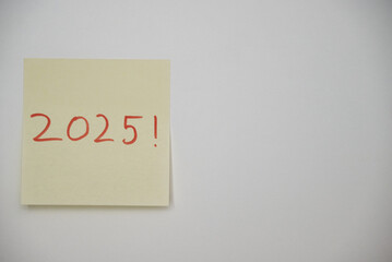 Poste-it note with the year 2025 written in red ink on a white background 