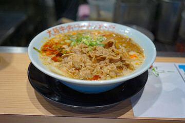 Close up ramen soup with noodles and meat in white bowl at ramen restaurant.
