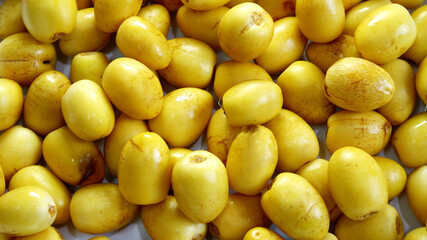 Date palm fruits background. Top view yellow date palm texture. Eating healthy, food texture, fresh fruit, agriculture, many, and organic concepts. Food texture background of ripe date palm fruit.