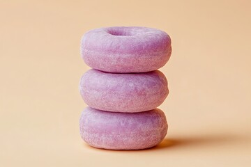 Three purple donuts stacked on top of each other against a light orange background.