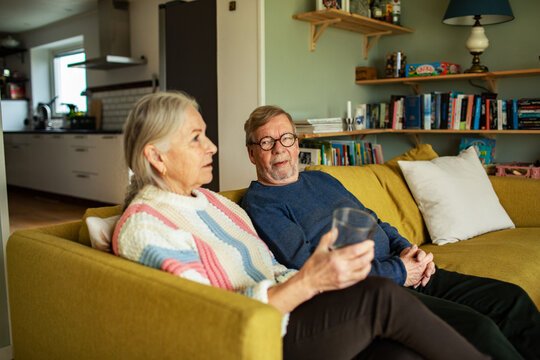 Senior couple sitting on a couch talking in a cozy living room