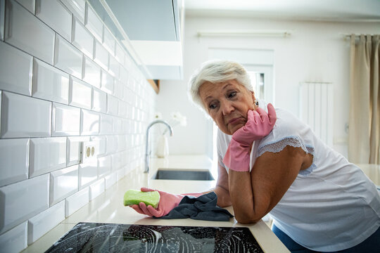 Senior woman tired of cleaning the kitchen with gloves on