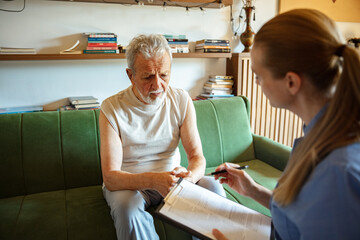 Senior man discussing health care plan with nurse or caregiver at home